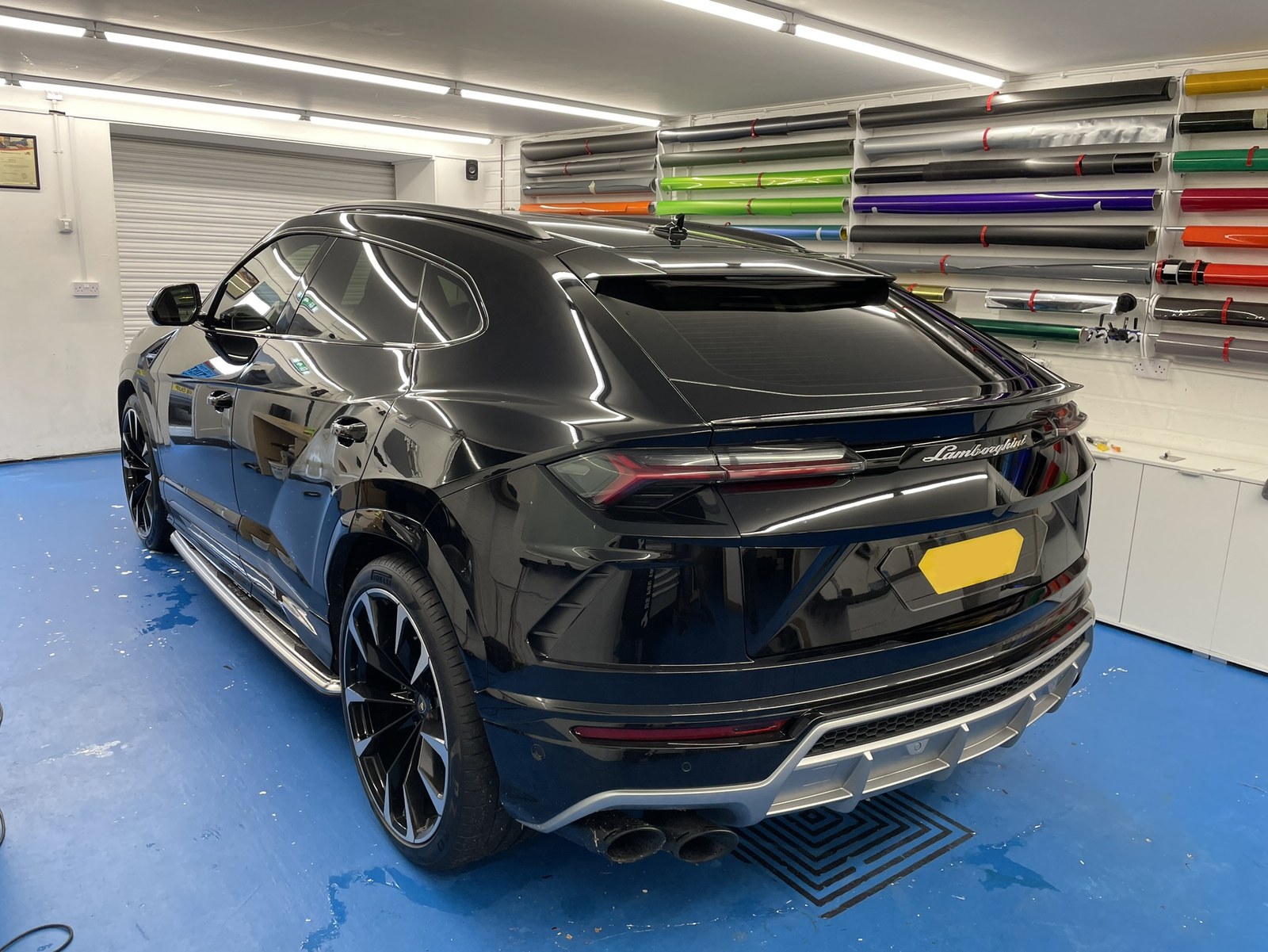 Black Lamborghini Urus with tinted rear glass in The Tint Factory workshop, film rolls on the wall