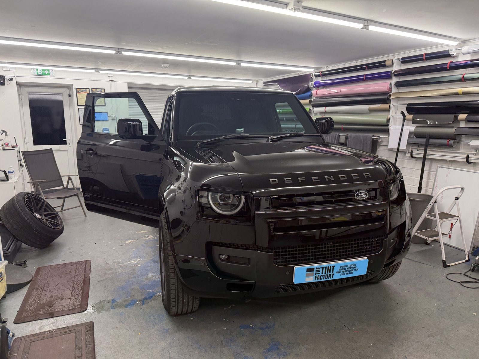 Land Rover Defender in The Tint Factory workshop with rolls of wrap and tint film on the wall