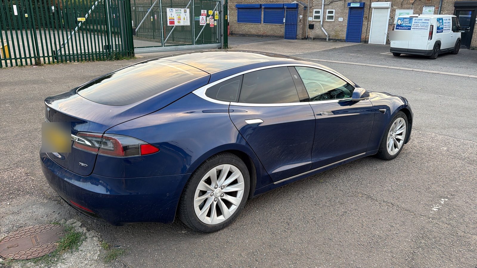 Blue Tesla Model S with tinted rear glass outside the workshop