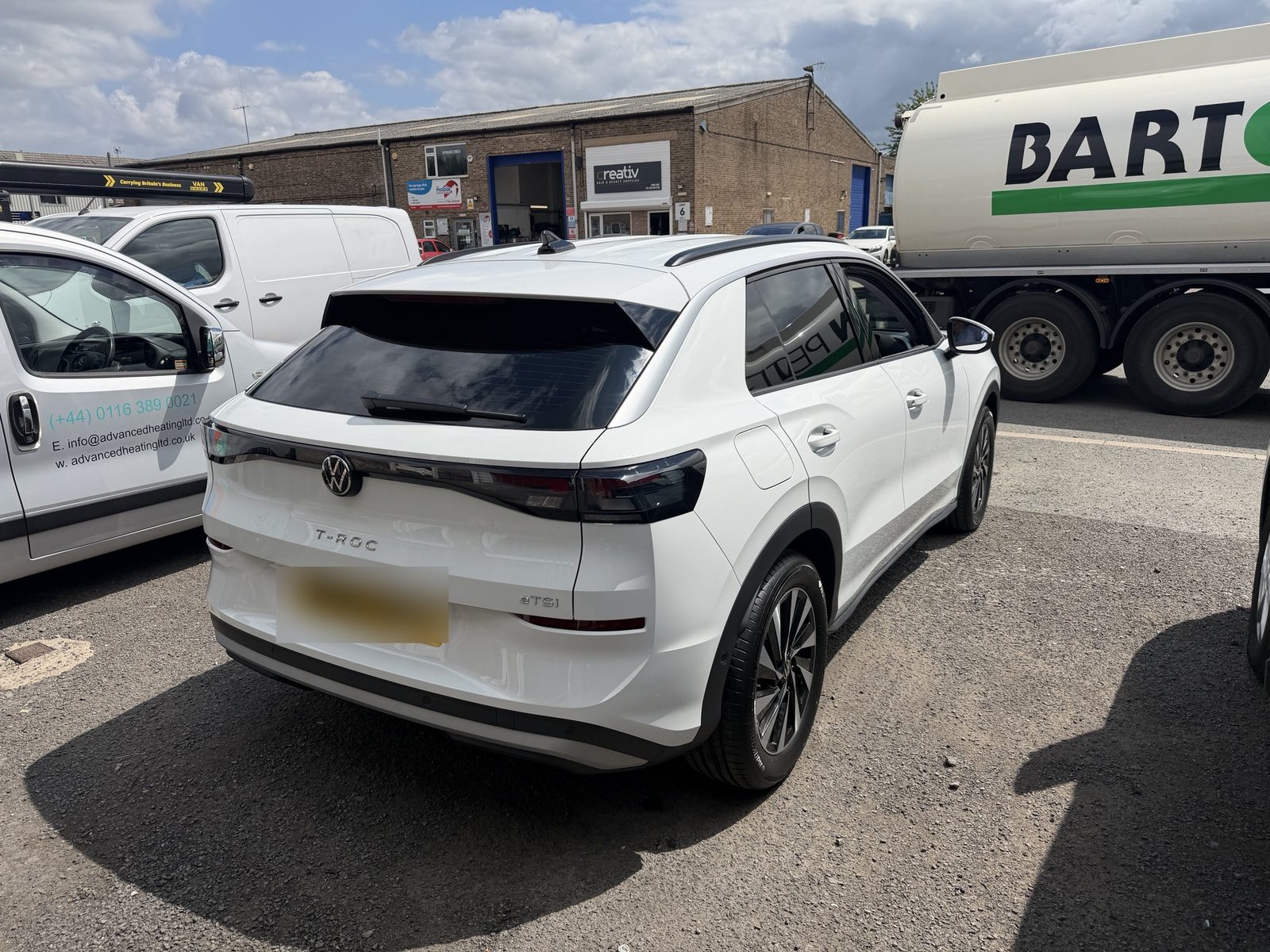 White Volkswagen T-Roc with tinted rear glass outside the workshop